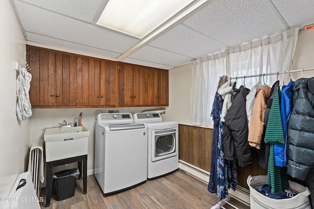 laundry area with cabinet space, wood finished floors, washing machine and dryer, and a baseboard radiator