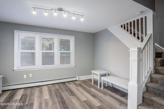 interior space with a baseboard heating unit and wood finished floors