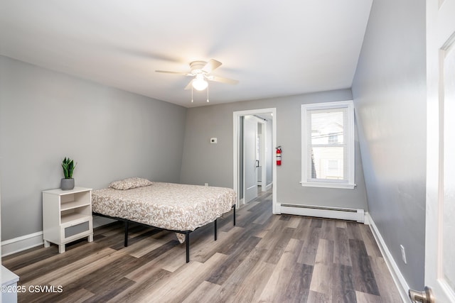 bedroom with baseboards, baseboard heating, and wood finished floors