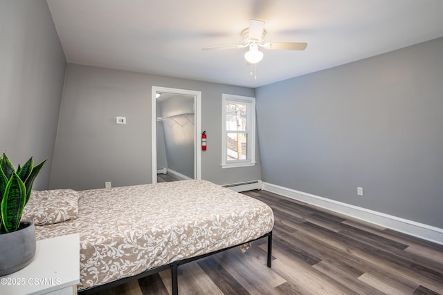 bedroom with ceiling fan, baseboards, baseboard heating, a closet, and dark wood-style flooring