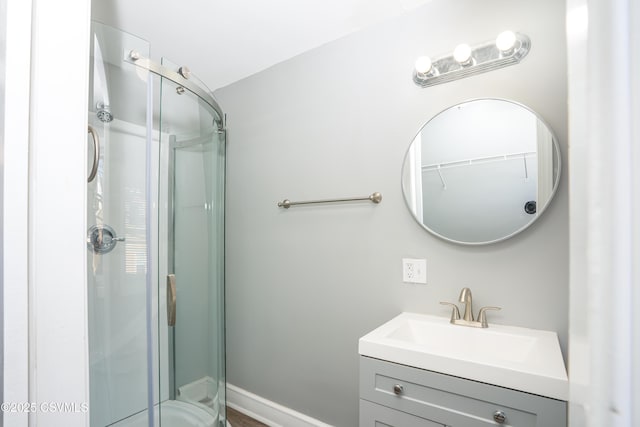 full bathroom featuring vanity, baseboards, and a stall shower