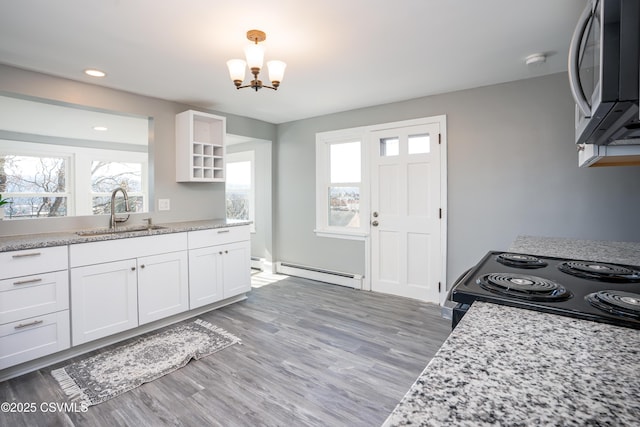 kitchen featuring a baseboard radiator, a sink, stainless steel microwave, black electric range oven, and a wealth of natural light