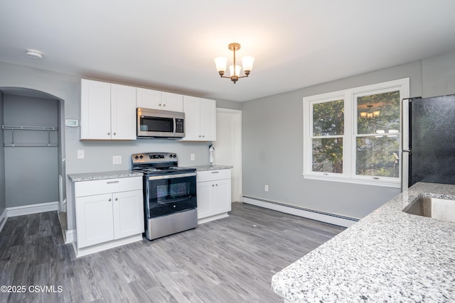 kitchen featuring light stone counters, arched walkways, appliances with stainless steel finishes, white cabinets, and a baseboard radiator