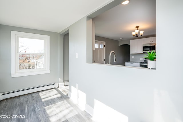 kitchen with stainless steel microwave, a healthy amount of sunlight, baseboard heating, and a baseboard radiator