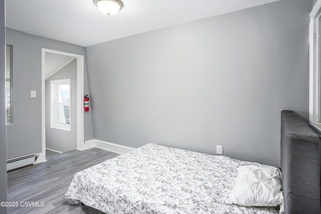 bedroom with baseboard heating, baseboards, and wood finished floors