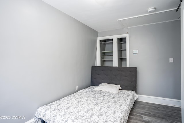 bedroom with baseboards, attic access, and dark wood finished floors