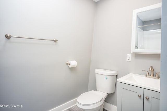 bathroom with toilet, vanity, baseboards, and wood finished floors