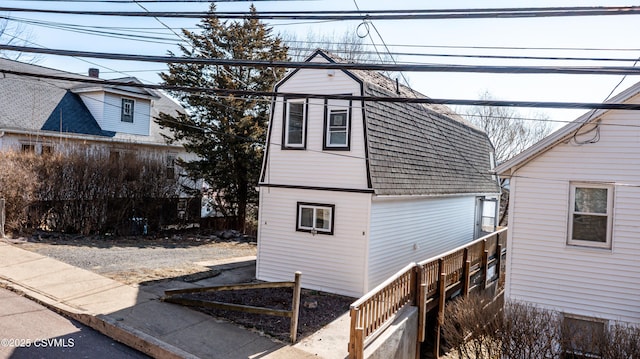 exterior space with a gambrel roof and roof with shingles