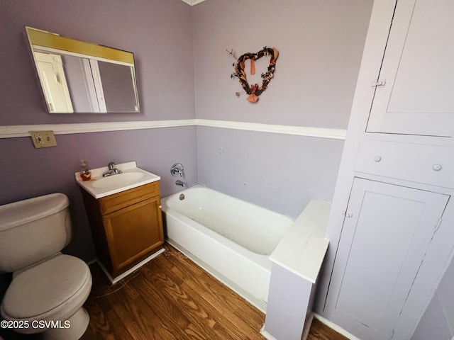 bathroom with toilet, electric panel, wood finished floors, a bath, and vanity