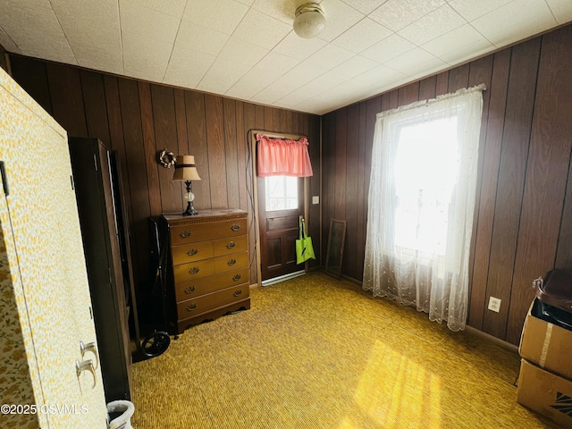 unfurnished bedroom with light carpet and wood walls