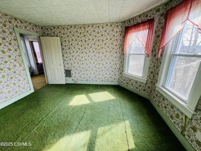 unfurnished room featuring wallpapered walls, visible vents, and baseboards