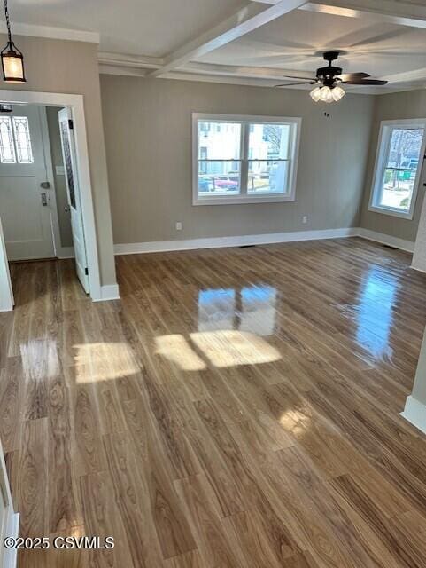 unfurnished living room featuring beamed ceiling, ceiling fan, baseboards, and wood finished floors