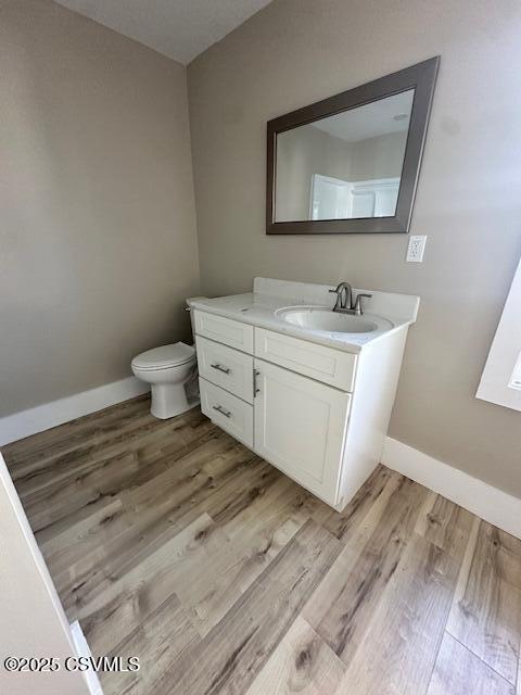 bathroom featuring toilet, vanity, baseboards, and wood finished floors