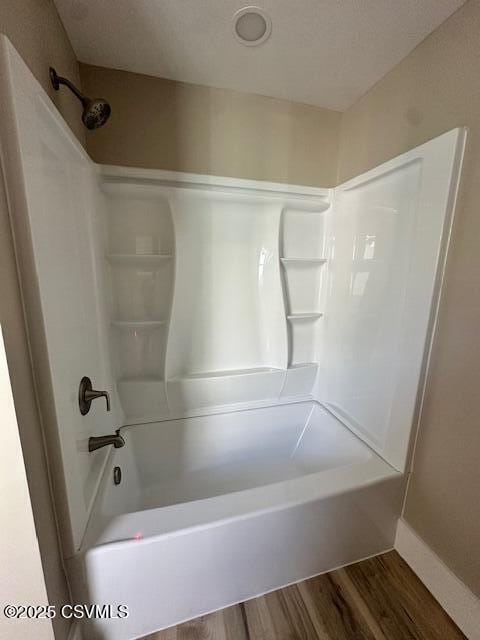 full bathroom with baseboards, wood finished floors, and bathtub / shower combination