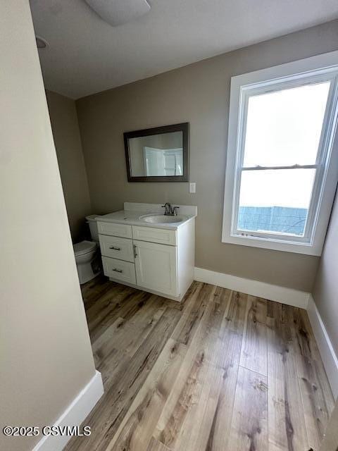 bathroom featuring vanity, toilet, wood finished floors, and baseboards