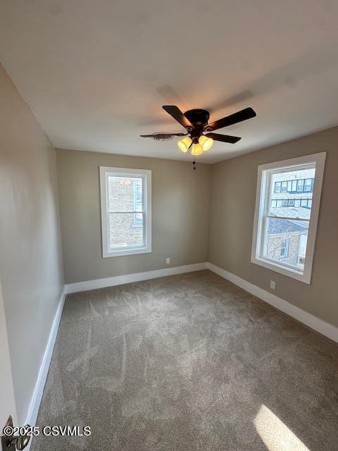 carpeted spare room with a ceiling fan and baseboards