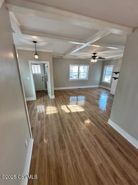 unfurnished living room featuring wood finished floors, baseboards, and ceiling fan