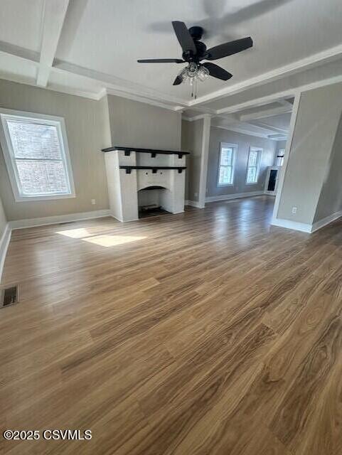 unfurnished living room featuring visible vents, beam ceiling, a ceiling fan, wood finished floors, and baseboards