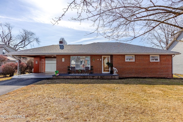 single story home with a front yard, brick siding, roof with shingles, and aphalt driveway