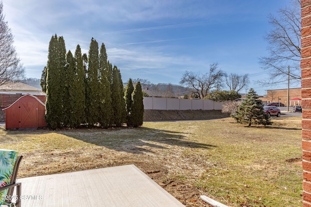 view of yard featuring a storage unit, an outdoor structure, and fence