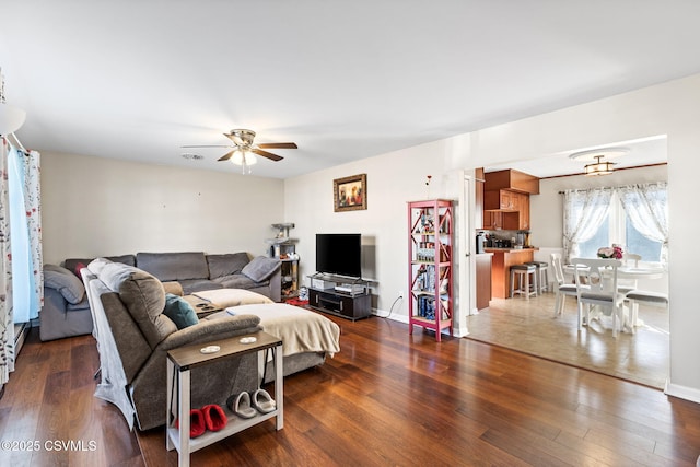 living room featuring dark wood finished floors, baseboards, and ceiling fan