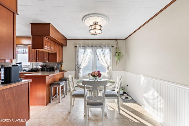 dining space featuring a wainscoted wall and ornamental molding