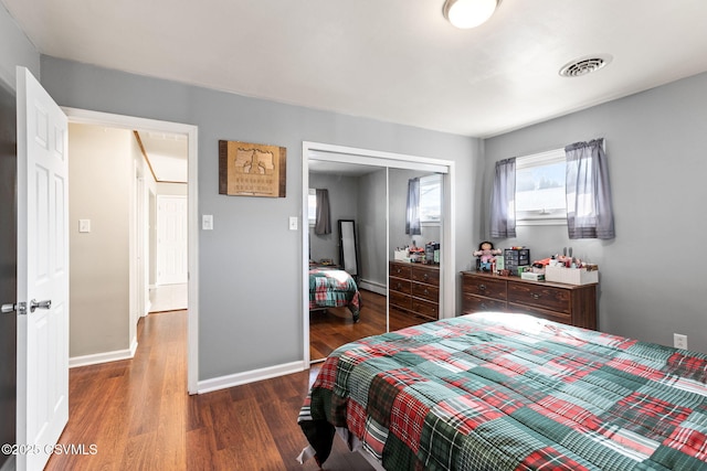 bedroom featuring wood finished floors, visible vents, a closet, and baseboards