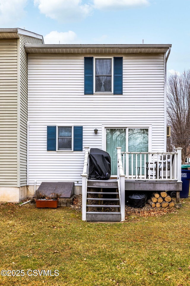 rear view of house with a yard and a wooden deck