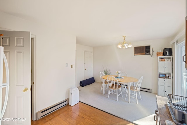 dining area featuring a notable chandelier, baseboard heating, an AC wall unit, and light wood-type flooring