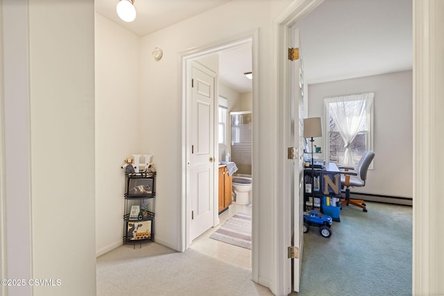 hallway with a baseboard heating unit and carpet floors