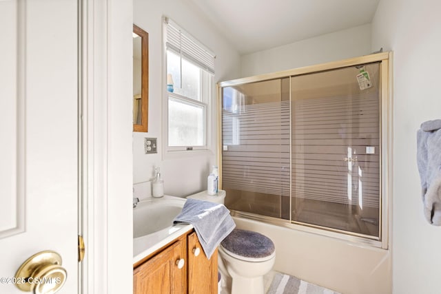 bathroom featuring toilet, vanity, and shower / bath combination with glass door