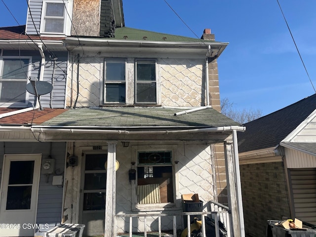 exterior space with a porch, a chimney, and roof with shingles