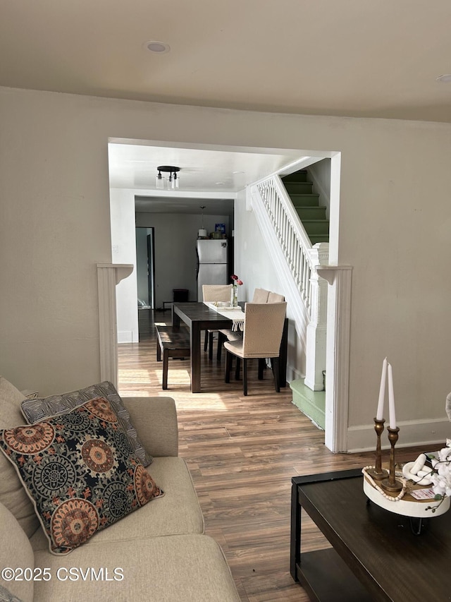 living room featuring stairway, baseboards, and wood finished floors