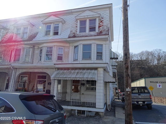 townhome / multi-family property featuring mansard roof and covered porch