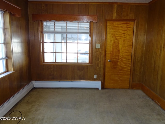 carpeted spare room with wooden walls, baseboard heating, and a baseboard heating unit