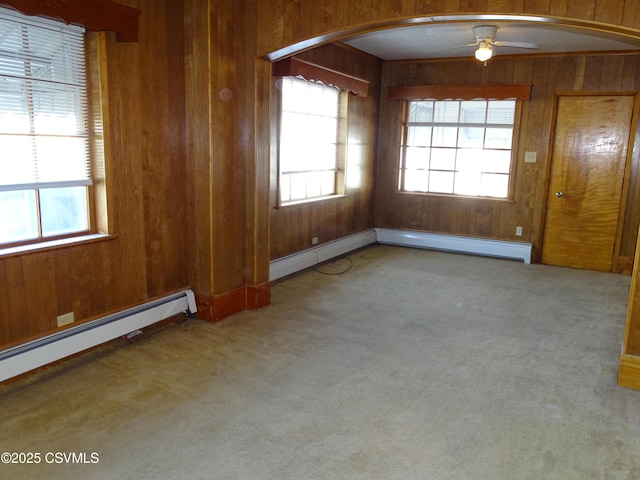 empty room featuring arched walkways, wood walls, and carpet