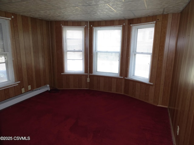 carpeted spare room featuring wooden walls and baseboard heating