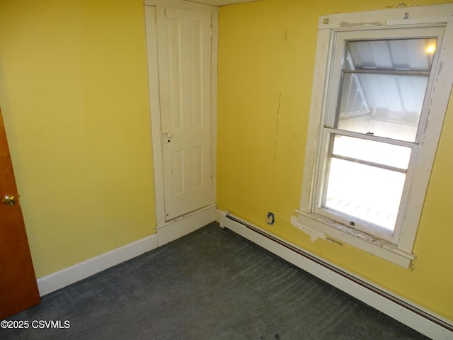 unfurnished room with a baseboard heating unit, baseboards, and dark carpet