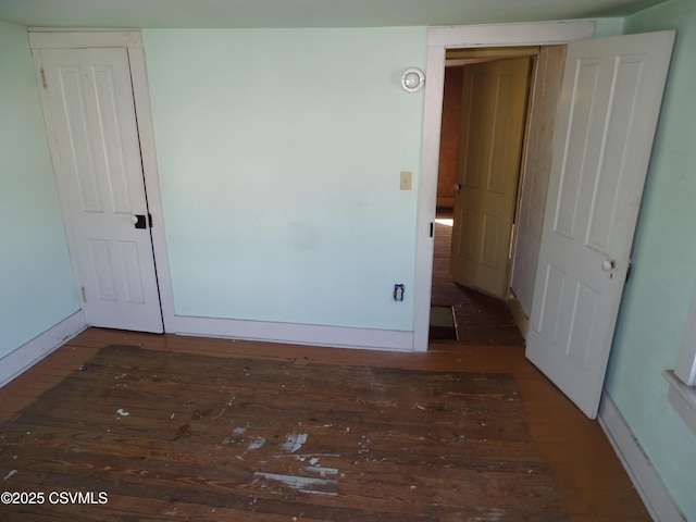 spare room featuring baseboards and hardwood / wood-style flooring