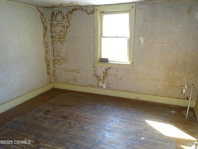 unfurnished room with baseboards and wood-type flooring