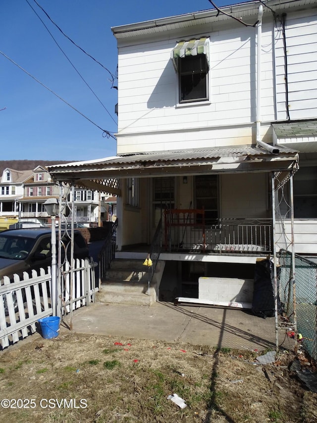 view of front facade featuring a porch, fence, and a carport