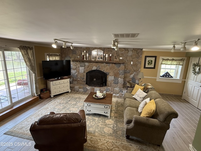 living room featuring track lighting, a wealth of natural light, wood finished floors, and visible vents