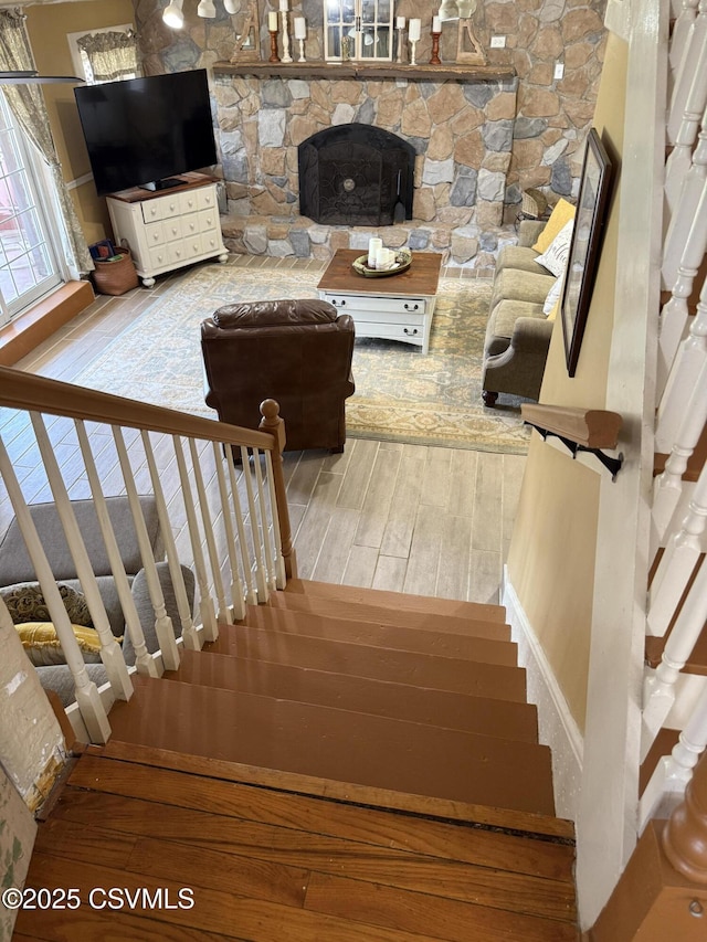 stairs with wood-type flooring and a fireplace