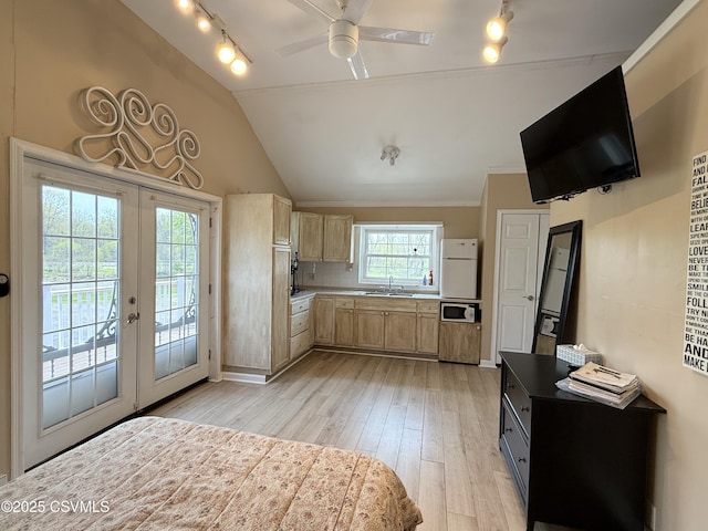 kitchen featuring a ceiling fan, light brown cabinets, light wood-type flooring, french doors, and a sink