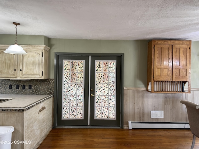 interior space featuring dark wood-style flooring, wainscoting, a textured ceiling, french doors, and a baseboard radiator