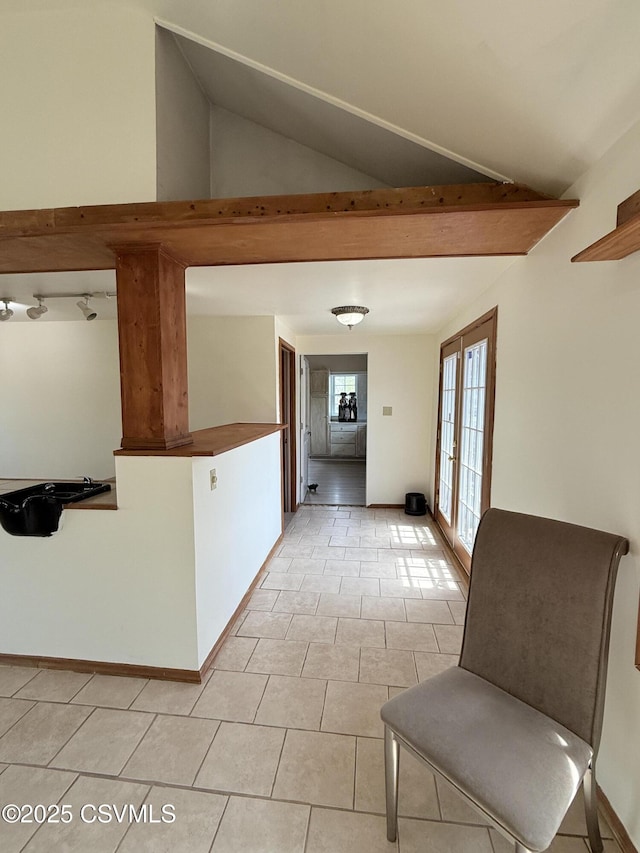 hallway with light tile patterned flooring and vaulted ceiling