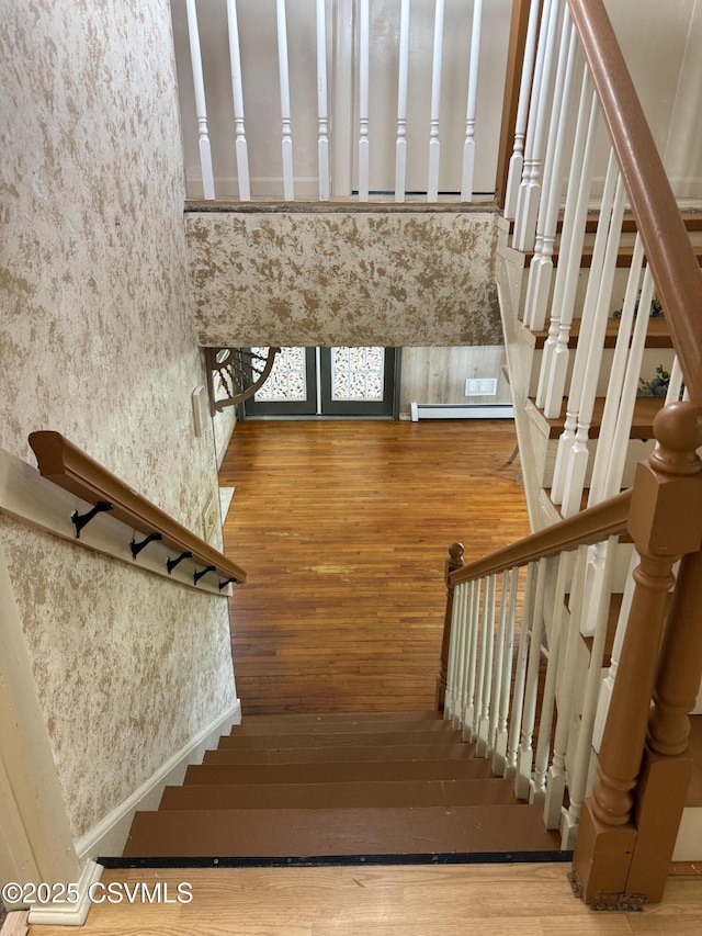 stairway with wallpapered walls and wood finished floors