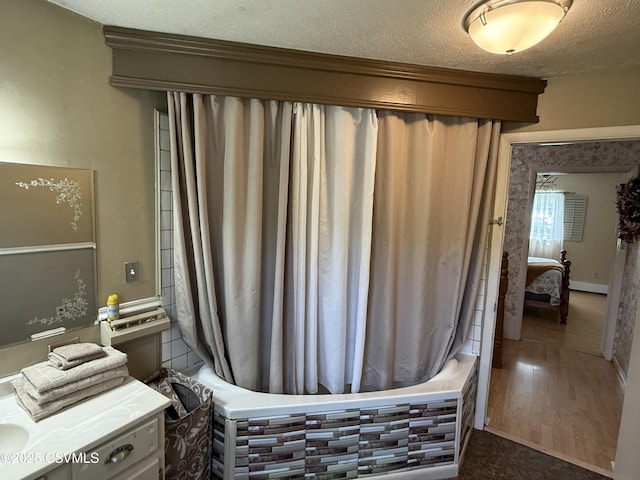 bathroom with wood finished floors, vanity, a textured ceiling, and shower / tub combo with curtain