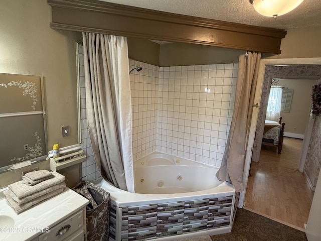 full bathroom with a textured ceiling, a combined bath / shower with jetted tub, wood finished floors, and vanity