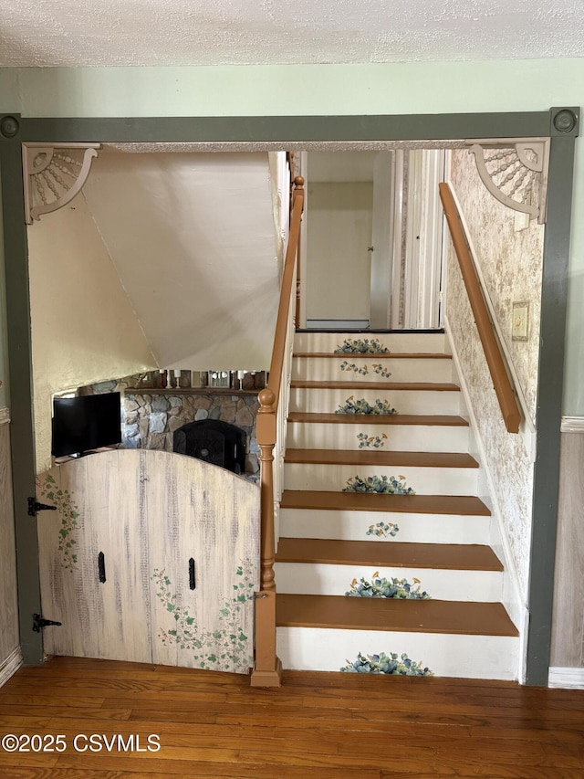 stairs featuring a textured ceiling and wood finished floors